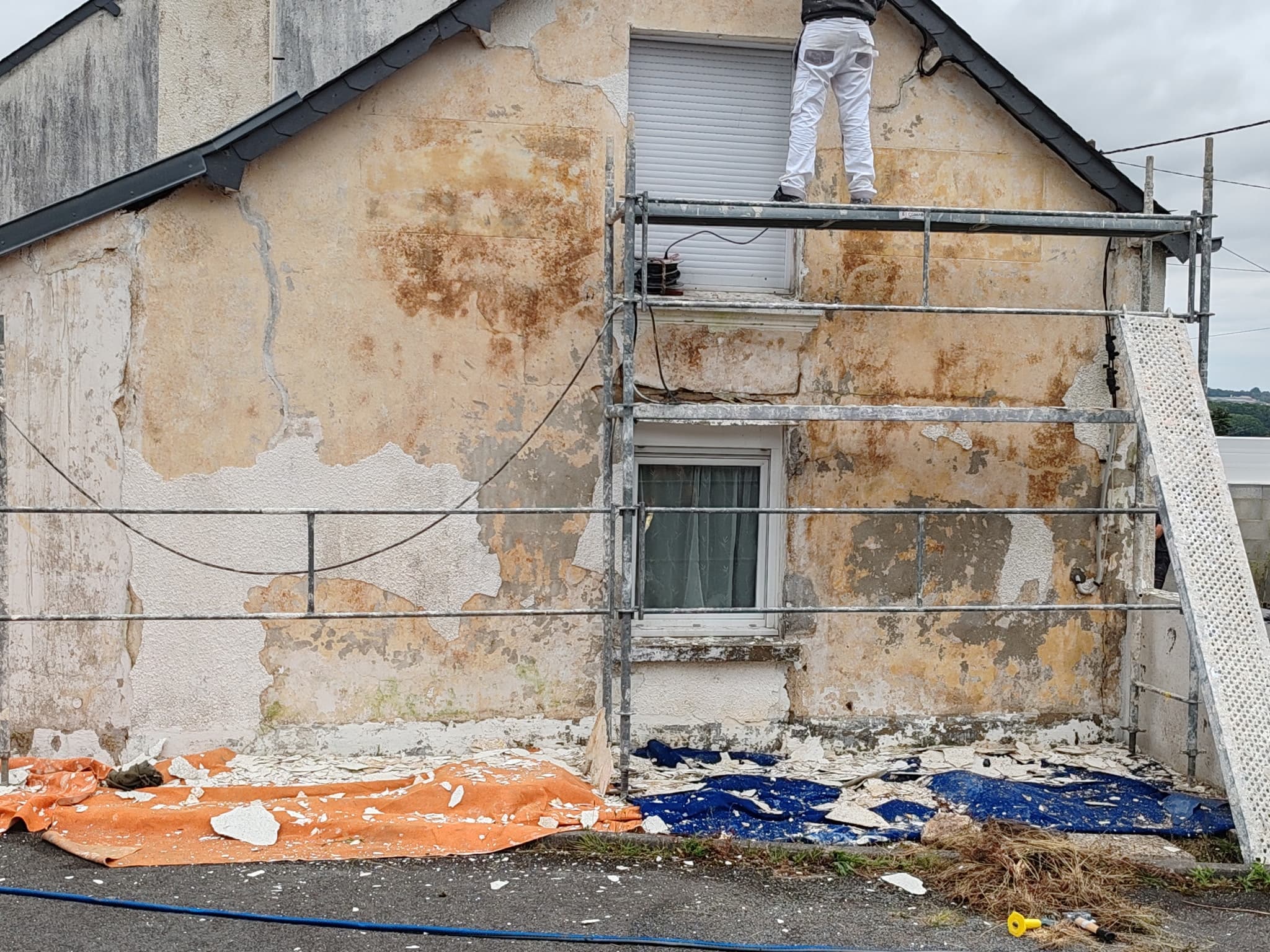 Ravalement d'une façade très abîmée en Morbihan, ouvrier sur échafaudage