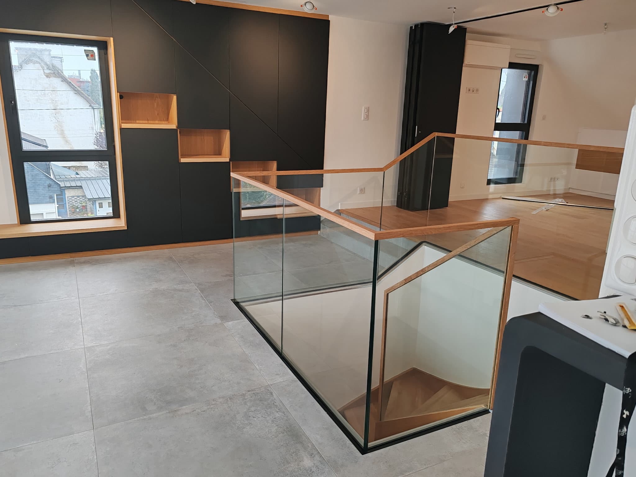 Intérieur design noir mat avec escalier verre et bois